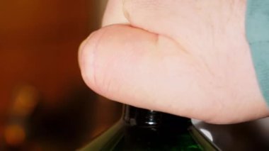 Adam bir şişe bira açıyor. Beyaz şapkalı yeşil plastik şişe. Erkek eli bir şişe taze biranın mantarını söküyor. Köpük bira şişesinden geliyor. Alkolik içecek. Yetişkinler için iç. Yakın plan.