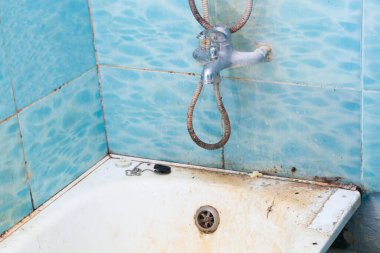Çok kirli banyo, duş, su musluğu ve fayanslar. Yoğun kirlenmiş beyaz banyo küveti. Küvetin temizlenmesi gerek. Kirli küvet. Banyoda bir deseni olan mavi fayanslar. Paslanmaz Çelik Banyo