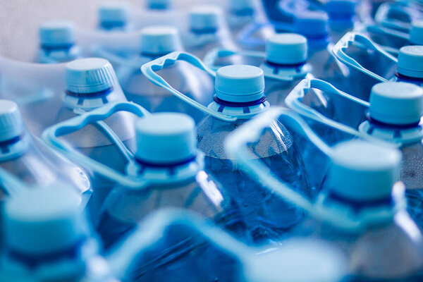 Many blue plastic bottles with blue caps with mineral water in a supermarket. Close Up. Main subject of a focus