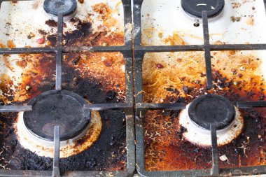 Kirli gaz sobası yüzeyi. İki gaz ocağı ve eski yiyecek ve içeceklerle çevrili bir gaz fırınının demir ızgarası. Üst bölge yüzeyi ve kullan-at kafaların yanmış yağlardan temizlenmesi gerekiyor. 