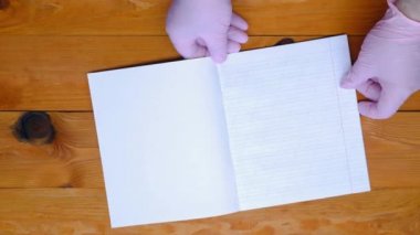 Okul öğretmeni eğik bir çizgide bir defter, renkli kalemler ve anaokulundaki tahta bir masada hecelemeyi öğrenmek için alfabe hazırlıyor. Uzayı metin için kopyala. Boş sayfa sayfası. Üst görünüm