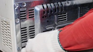 Buzdolabı tamir servisi. Usta vidaları tornavidayla söküyor. Tamirci soğutma ekipmanının örtüsünü kaldırır. Motor çok kirli ve tozlu. Soğutucu ve radyatör