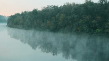 Suyun üstünde sigara iç. Sis sabahın erken saatlerinde nehrin üzerinde yüzer. Yeşil ormanın arka planında güzel bir göl. Su yüzeyi. Doğanın büyüleyici mucizeleri. Metin için alanı kopyala