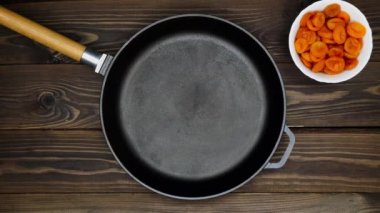 Tahta bir masaya demir tepsi dök. Bir şef kızartma için yemek hazırlar. Kumkatlar, kurutulmuş kayısılar, bir dalda vişneli domatesler, Red Hot Chili Peppers, Black Peppercorn, Mortar & Pestles. Boşluk metnini kopyala