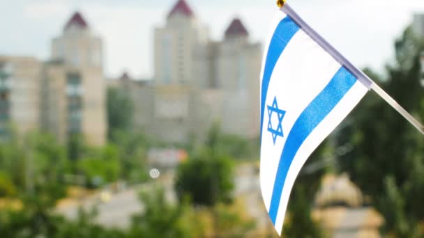 以色列国旗映衬着蓝天和城市街道 以色列国旗是蓝色的六边形 白色背景上有条纹 以色列国旗飘扬 以色列的节日旗帜在阳光下升起 复制空间 — 图库视频影像