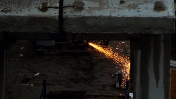 火花从建筑工地的锯子上飞散 在房屋建造中 一个工人用磨床锯断了一个零件 雨落在水泥板上 工业生产中的大火花飞舞 — 图库视频影像