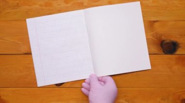 Okula dönelim. Masada boş bir sayfa olan defter. Yamuk bir çizgideki günlük, portakal rengi ahşap bir masanın arka planında yatıyor. Okul malzemeleri, renkli kalemler ve İngiliz alfabesinin harfleri.