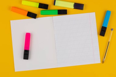 Not defteri sarı arkaplanda metin, renkli kalemler ve kalemler için kopyalama alanı var. Okula dönelim. Egzersiz kitabında eğik çizgiler olan boş bir kağıt. Okul malzemeleri. Üst görünüm