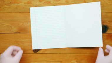 School instructor lays out a notebook in a line, colored pens and the alphabet for learning spelling on a wooden table in the preschool classroom. Copy space for text. Blank sheet page. Top view