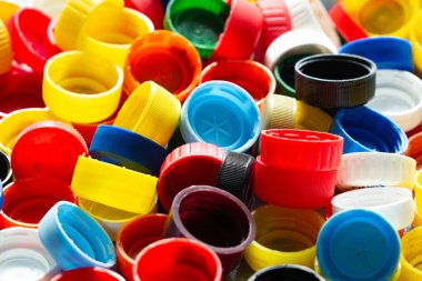 Plastik şişelerden kapaklar. Bir sürü renkli plastik şişe kapağı. Kimya endüstrisinin ürünü. Çevre için tehdit. Plastik kirliliği. Ekolojik sorunlar. Üretimde geri dönüşüm materyalleri