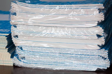 Defterler yığını. Okula dönelim. Sınıftaki masanın üzerinde bir paket mavi okul not defteri. Bir yığın egzersiz kitabı. Anaokulu eğitimi için kareli matematik defterleri paketliyorum. Sınıf odası. Yakın plan.