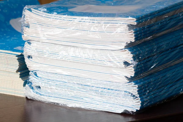 Stack of Notebooks. Back to school. A pack of blue school notebooks on the table in a classroom. Stack of exercise books. Packing checkered math notebooks for preschool education. Class room. Close-up