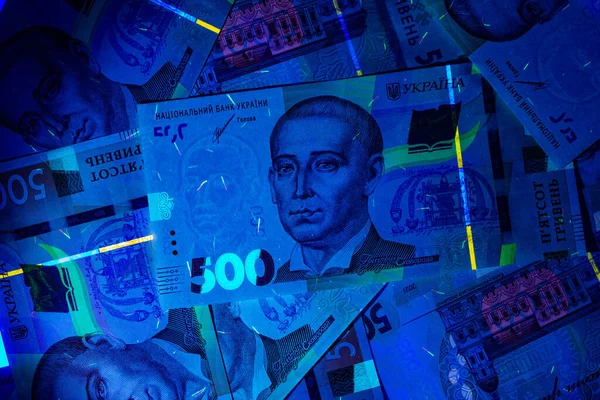 Ukrainian currency hryvnia in ultraviolet rays. The beam of the UV flashlight on the Banknotes of five hundred UA hryvnias. Watermarks and strong degrees of fraud protection. Beautiful money. Close-up