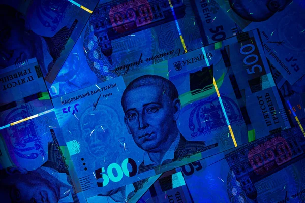 Ukrainian currency hryvnia in ultraviolet rays. The beam of the UV flashlight on the Banknotes of five hundred UA hryvnias. Watermarks and strong degrees of fraud protection. Beautiful money. Close-up