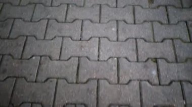 The road with the eyes of a walking person. View of the pavement paved with gray figured tiles from the level of human growth. Pedestrian sidewalk under human feet. Top view