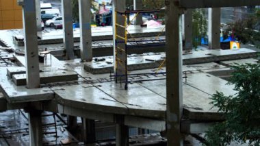 Yağmurda inşaat alanında. İnşaatçılar kötü hava koşulları nedeniyle işyerinden ayrıldılar. Beton levhalar ve önceden hazırlanmış beton yığınları suyla doludur. İşçiler zorla mola verdiler.