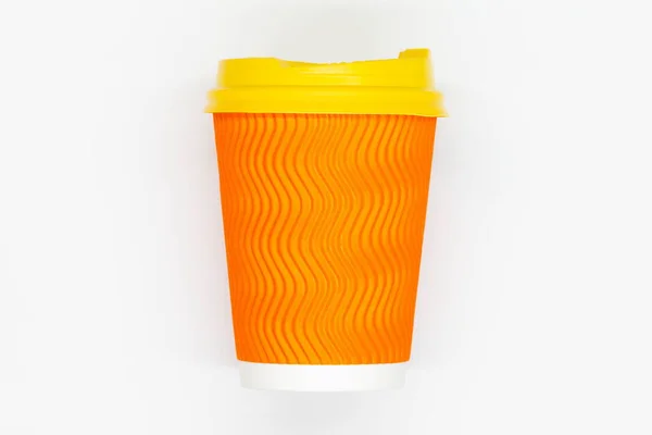 Paper coffee cup. Orange craft paper coffee cup with yellow plastic lid. Disposable cup for safe drinking of hot and cold drinks. Safe ribbed capacity. Container for healthy beverage. Isolated. Close-up