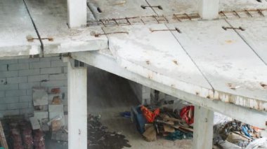 Yağmurda inşaat alanında. İnşaatçılar kötü hava koşulları nedeniyle işyerinden ayrıldılar. Beton levhalar ve önceden hazırlanmış beton yığınları suyla doludur. İşçiler zorla mola verdiler.