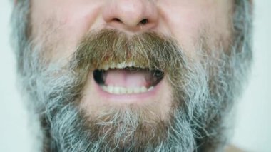 An angry man is screaming. An evil man with a big unkempt gray brown beard, mustache and glasses swears a lot. Mentally ill man got angry and screams. Human anger. The man is very angry. Slow motion 