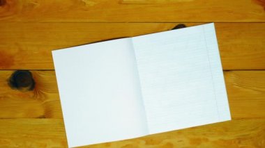 Back to school. Notebook with a blank page on the table. Diary in an oblique line on the orange wooden table background. School supplies, colored pens and letters of the English alphabet. Top view