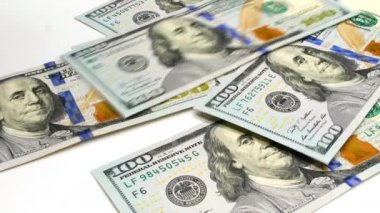 Recalculation of money. US dollars banknotes are falling on a white background. One hundred dollars banknotes pack. Dollar banknotes close-up. USA currency. Money is falling. High quality 4k footage