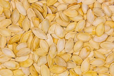 Dried pumpkin seeds in husks. Yellow pumpkin seeds. Wallpaper, background. Flat oval seed of squash. Edible seed of a pumpkin. Healthy food. Natural product. Roasted snack. Pepita. Top view. Close-up