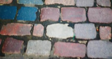 The road is moving. The movement of the road from the pavers. Moving paving stones, top view through the eyes of a person. Pavement from old beautiful multi-colored stones. Sidewalk garbage