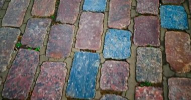 The road is moving. The movement of the road from the pavers. Moving paving stones, top view through the eyes of a person. Pavement from old beautiful multi-colored stones. Sidewalk cigarette butts