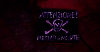 Attention! Deadly danger. Warning sign in Italian. Human skull and crossbones drawing with white paint on a black board. Scary concept illustration for Halloween of a skull with bones and rifle
