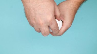 Bir erkek eli tıbbi kapsüllerle şişeyi açar ve avucuna ilaç hapları döker. İlaç şişesinde ve elinde beyaz ilaçlar var. Sağlık hizmeti. Eczane ve tedavi konsepti. Yakın plan. Üst görünüm