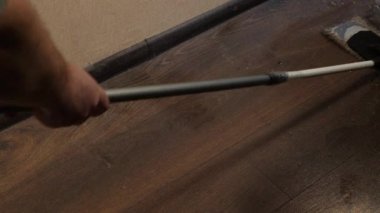 Çok kirli bir zemin bir paspasla yıkanır. Yerleri paspaslıyorum. Bir adam acemice çok tozlu kahverengi bir zemini ıslak bir paspasla temizler. Daireyi temizliyorum. Sağlık hizmetleri. Evde bakım.