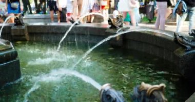 Birçok insanın yürüdüğü ve dinlendiği büyük bir parkta güzel bir şehir çeşmesi. Sıcak ve güneşli bir günde şehir çeşmesinde serin su. Kavurucu güneşin altındaki su. Tatil ve dinlenme