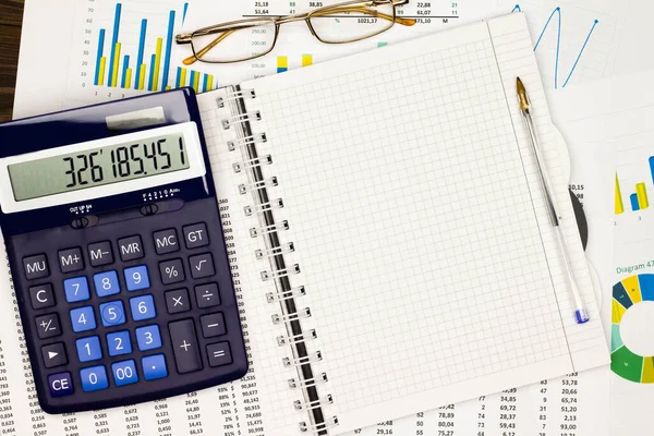 Top view office table desk. Financial report. Flat lay. Workspace with Business office supplies, numbers and empty sheet of paper, diagrams, pen, glasses, calculator. Copy space for text. Top view