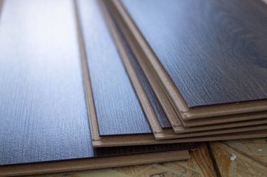 Laminate. Evin zeminine kahverengimsi lamine döşemek. Daire tadilatı. Eski katı yenisiyle değiştirmek. Laminate çarşafları ahşap bir zemine yerleştirilir.