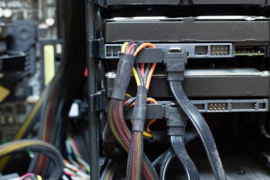 Bağlantıları olan çok kirli kablolar bilgisayarın sabit diskine bağlıdır. HDD ve SSD diski. Örgü ambalajında eski renkli kablolar. Elektronik ekipmanlarda sıkışmış elektrik teli. Elektronik onarım