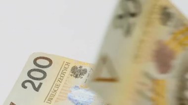 Polonya parası Zloty. Paranın yeniden hesaplanması. İzole edilmiş. El, kağıt para sayıyor. Yüz iki yüz zloti. Polonya banknotları beyaz arka planda masanın üzerine düşüyor. Yakın plan..