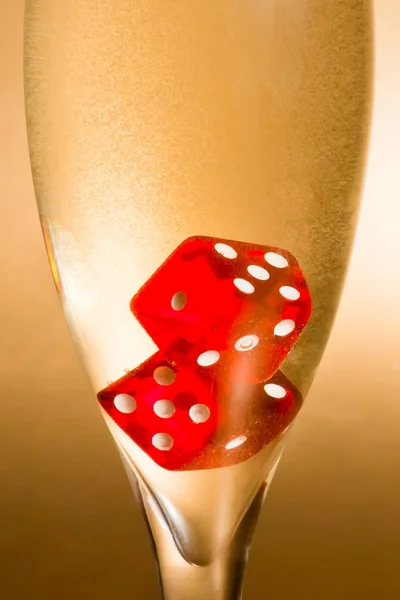 Detail of a flute with inside red dice and gold bubbles — Stock Photo, Image