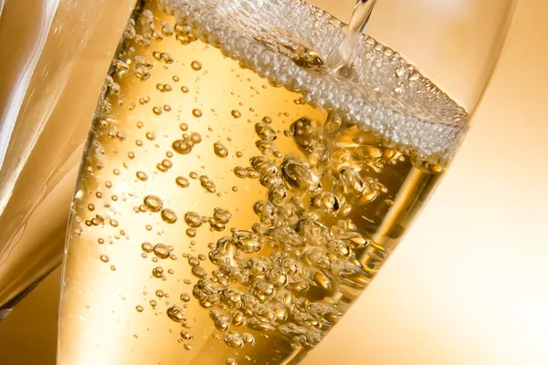 Leere Champagnergläser und ein gefülltes Glas Stockbild