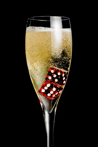 Champagne flute with golden bubbles and red dice — Stock Photo, Image