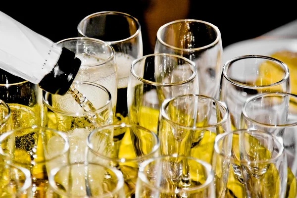 Grupo de flautas de champán en mesa festiva y una se está llenando — Foto de Stock