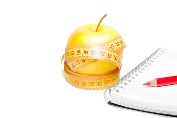 An apple with tape measure near notebook — Stock Photo, Image