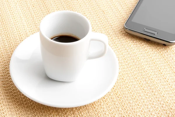 Café expreso oscuro en una taza cerca del teléfono inteligente — Foto de Stock