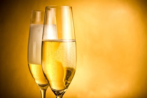 Two flutes of champagne with golden bubbles and white foam — Stock Photo, Image