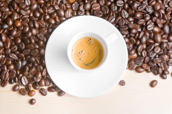 Parte superior de la vista de la taza blanca con café expreso cerca de granos de café —  Fotos de Stock