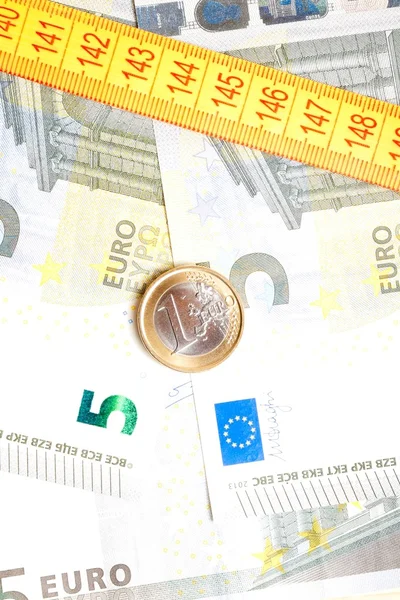 Money euro coin on banknotes near measure tape — Stock Photo, Image