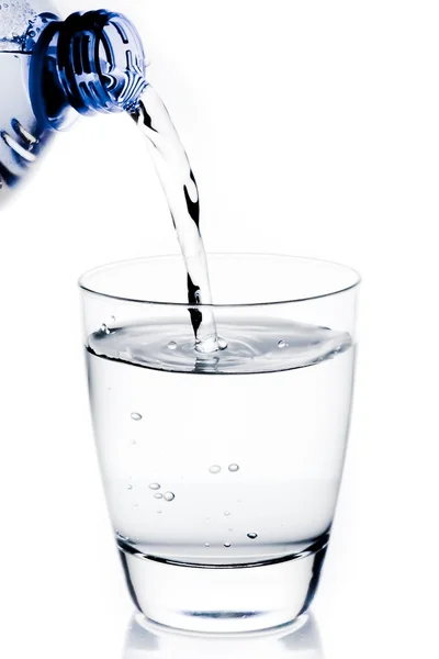 Заполнение стакана водой через голубую бутылку — стоковое фото