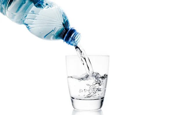 Gießen Sie ein Glas mit Wasser durch kleine blaue Flasche — Stockfoto