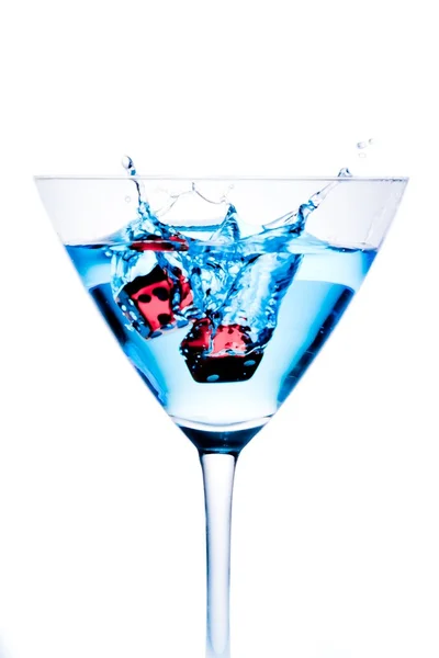 Red dice falling in the blue cocktail glass with splashes — Stock Photo, Image