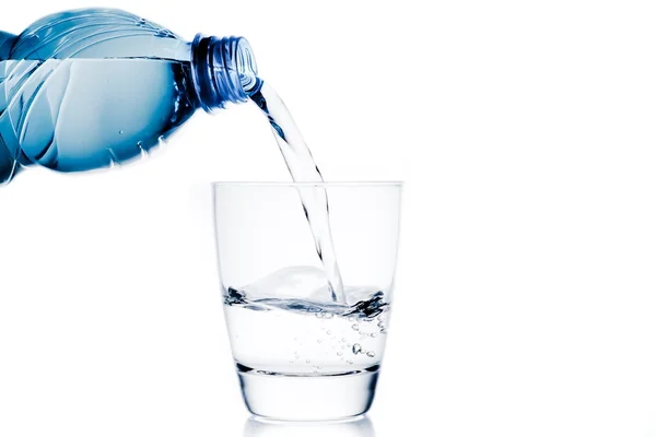 Een glas met water trog gieten beetje blauwe fles en ruimte voor tekst — Stockfoto