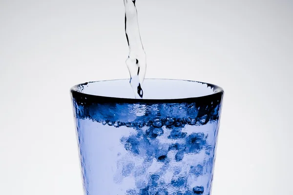 Enchendo um copo azul com água pura e bolhas — Fotografia de Stock